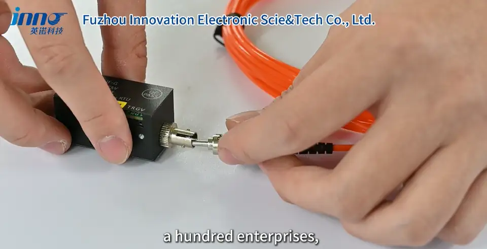 Hands connecting an orange fiber optic temperature probe to a monitoring instrument