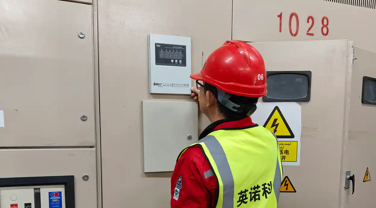 Engineer inspecting a fiber optic temperature monitoring panel in an electrical cabinet